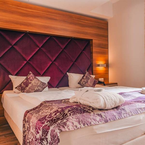 Double bed in the apartment at Arkona Strandresidenzen Binz with cozy lighting and a velvet headboard in purple