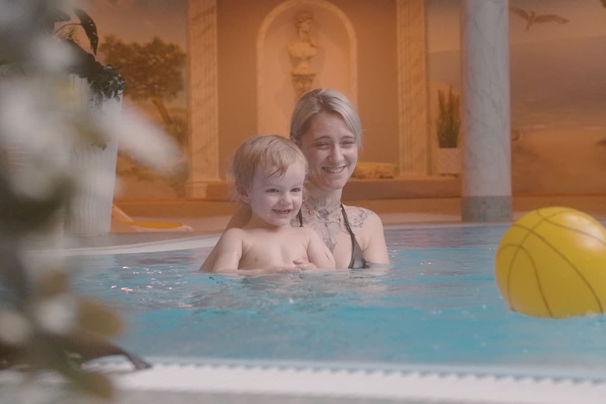 Mother and child playing with a yellow water ball in the luxurious hotel pool at Arkona Strandhotel