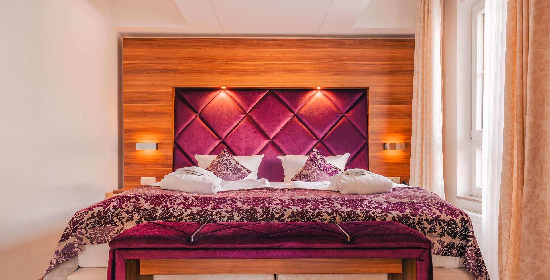 Elegant double bed with purple padded headboard in the Arkona Strandresidenzen apartment in Binz on Rügen